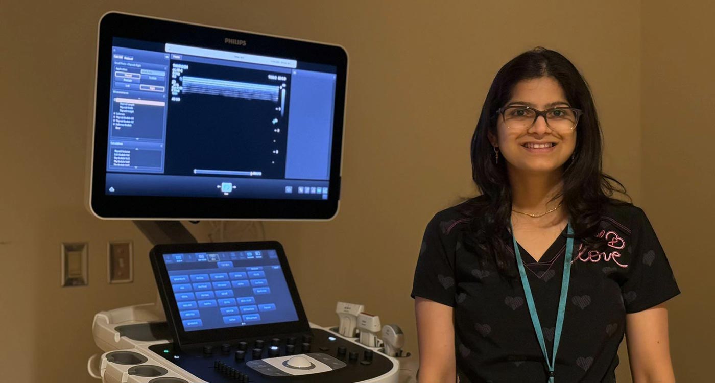 Heena, an Ultrasound Technologist, stands with an ultrasound machine